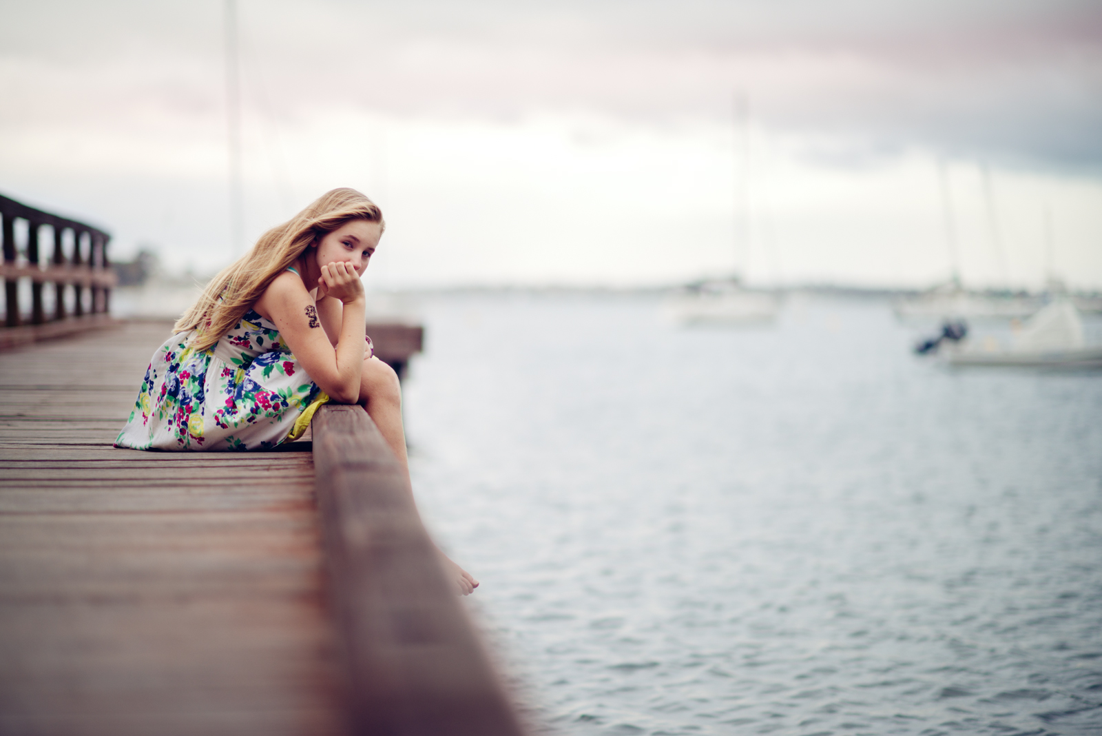 Girl sitting on a dock on a cloudy day